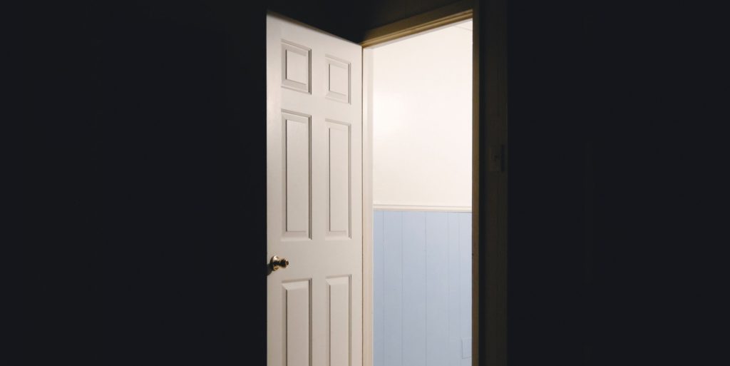 An open door allowing light to shine into a dark room.