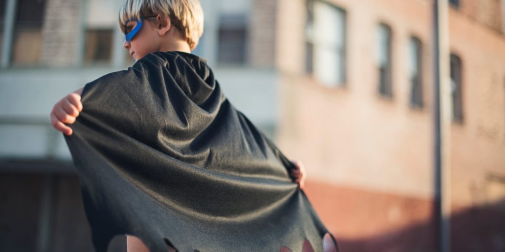 selective focus photography of boy wearing black Batman cape