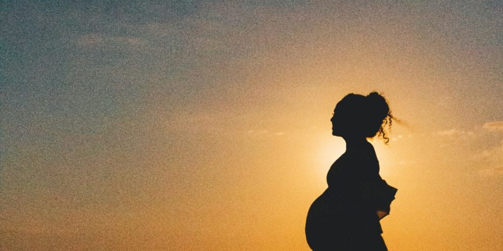 silhouette of woman standing on beach during sunset