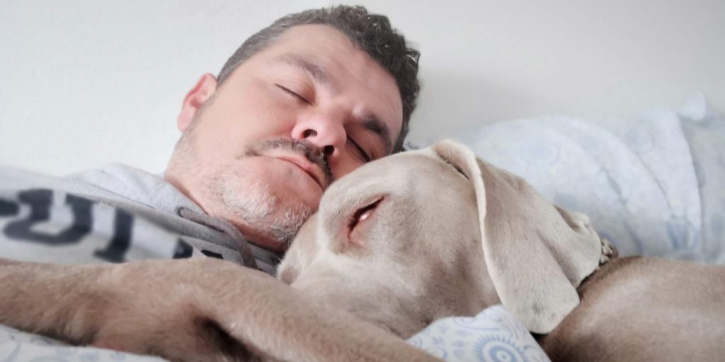 man laying on bed beside dog