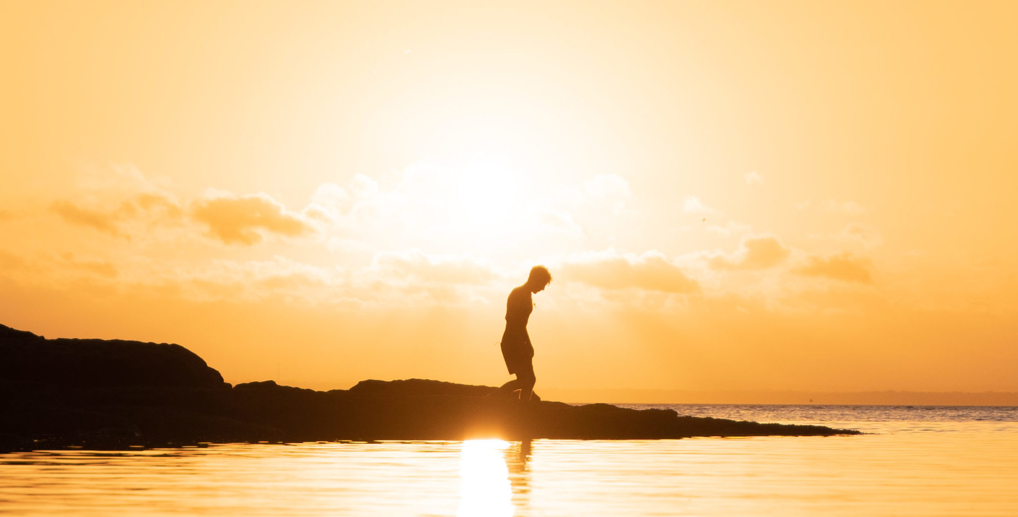Silhouette of man standing on seashore during sunset