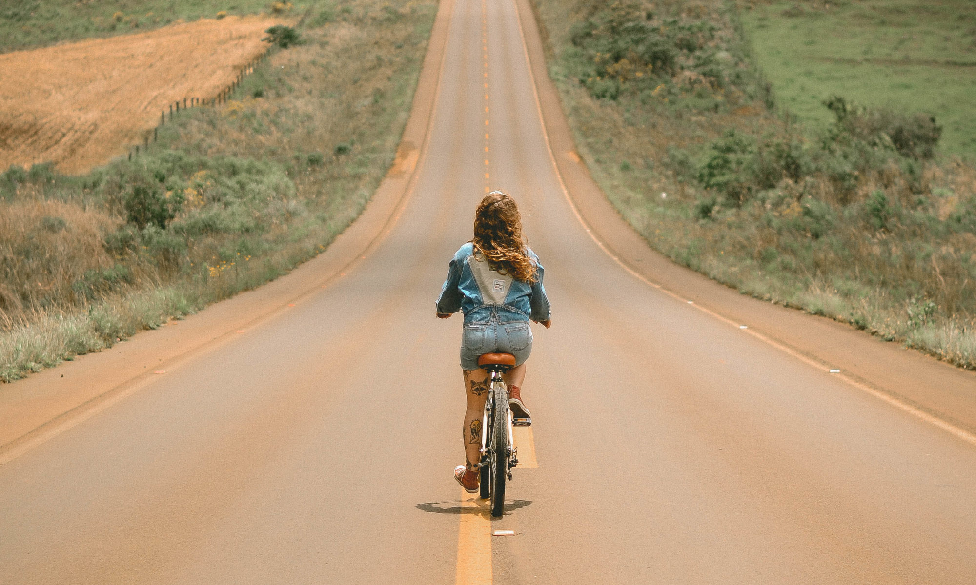 Girl riding bike in the middle of the road during day