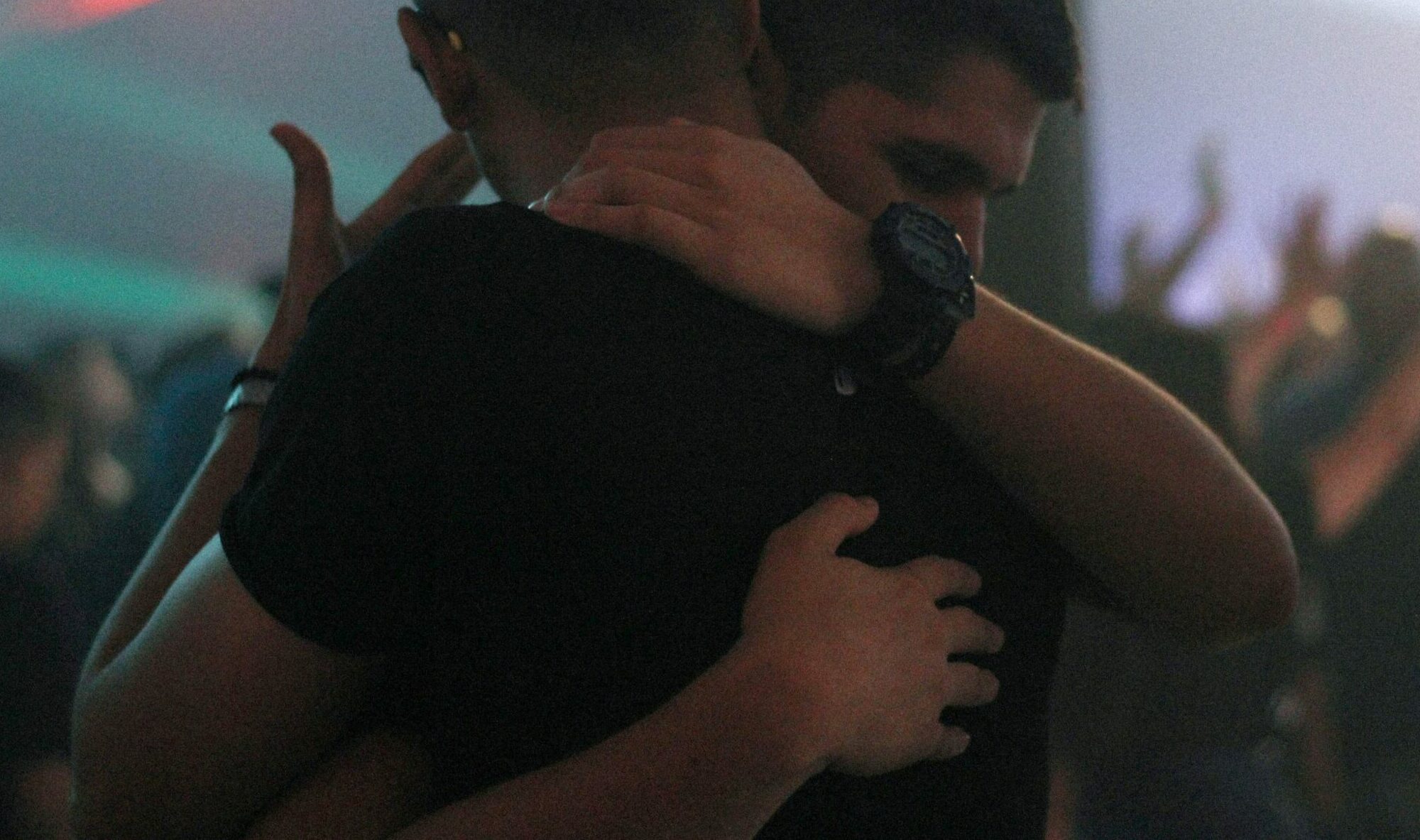 Men Hugging In a Crowded Room
