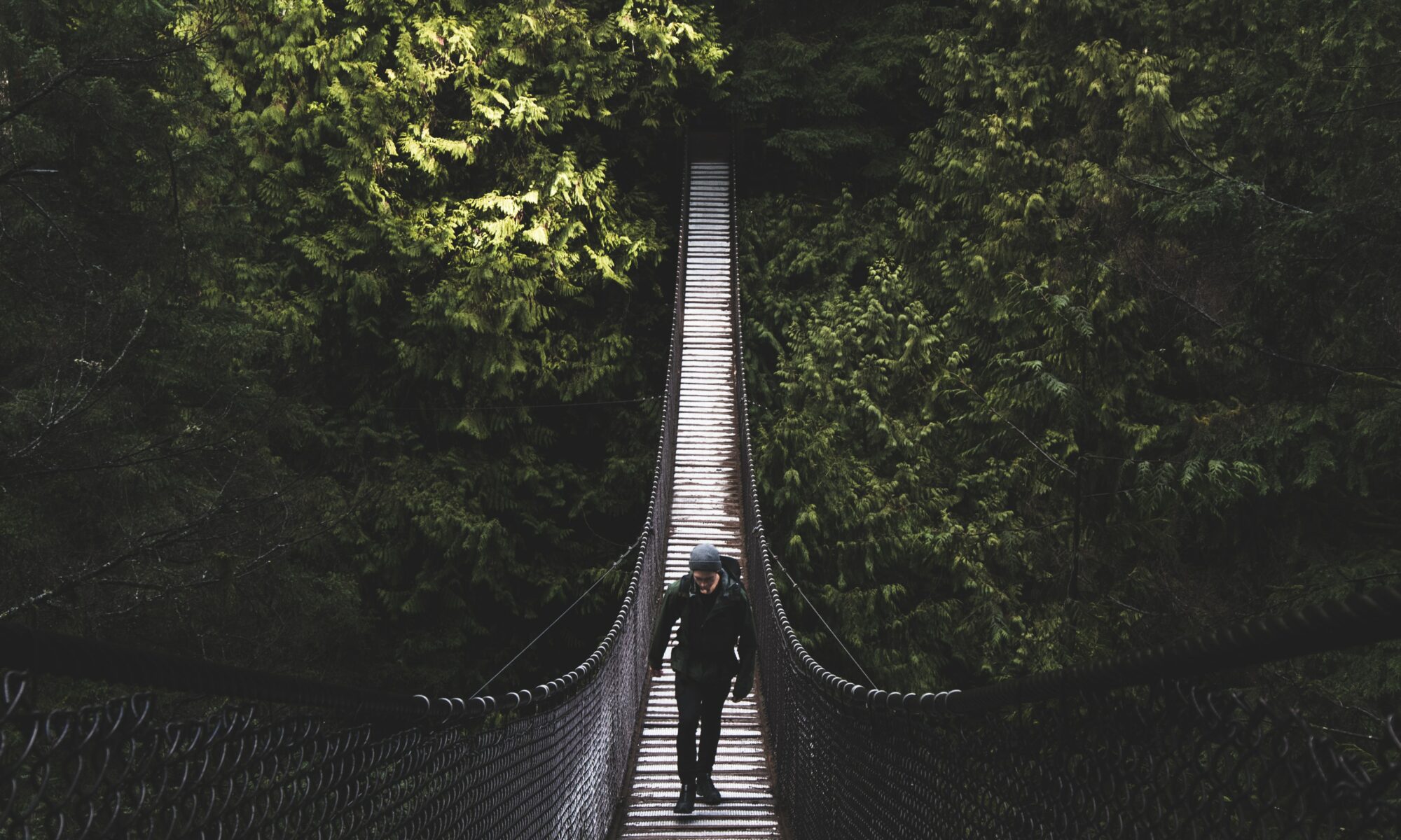 photo of man walking of foot bridge