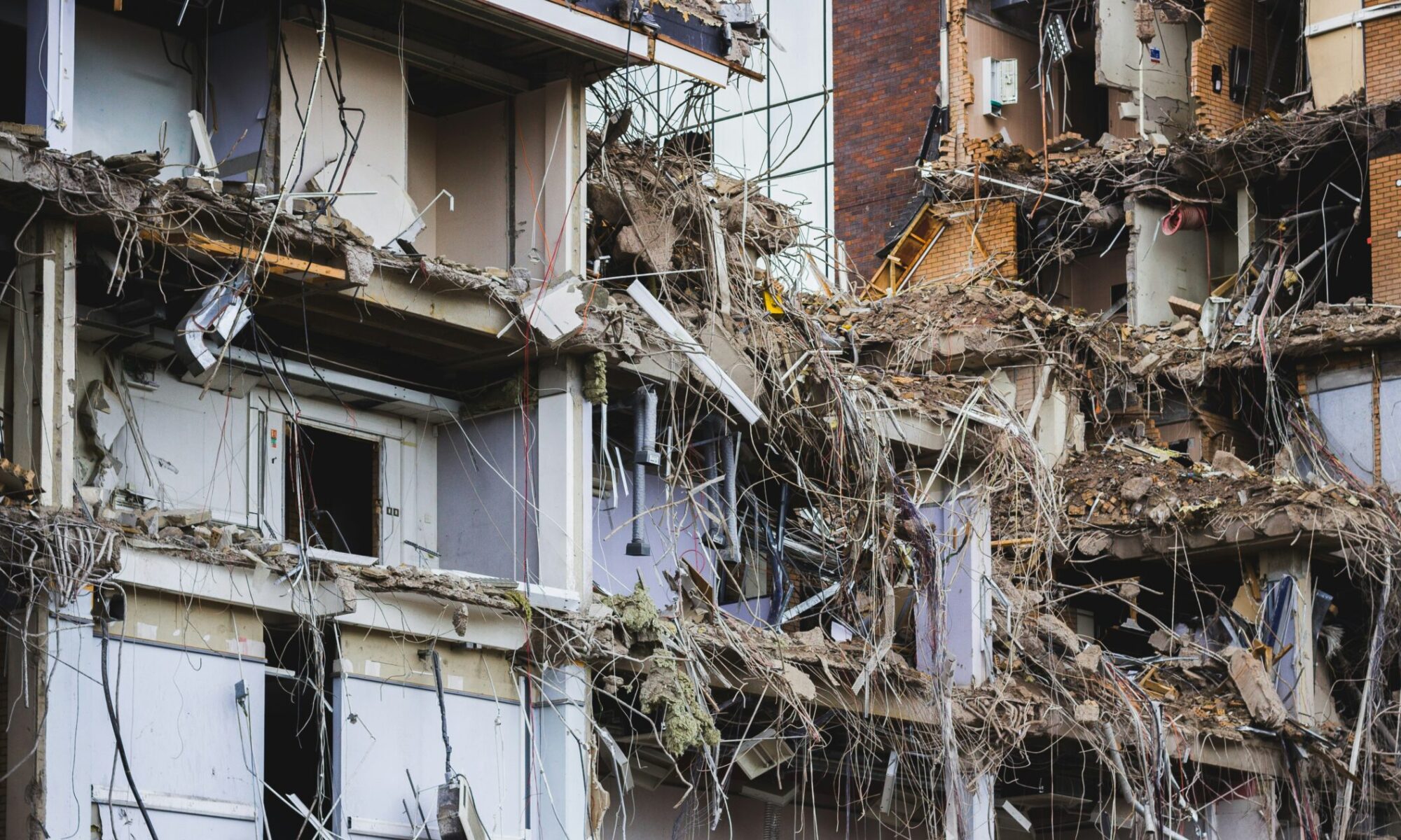 The facade of an office block removed to expose office spaces, cables, rooms and the structure.